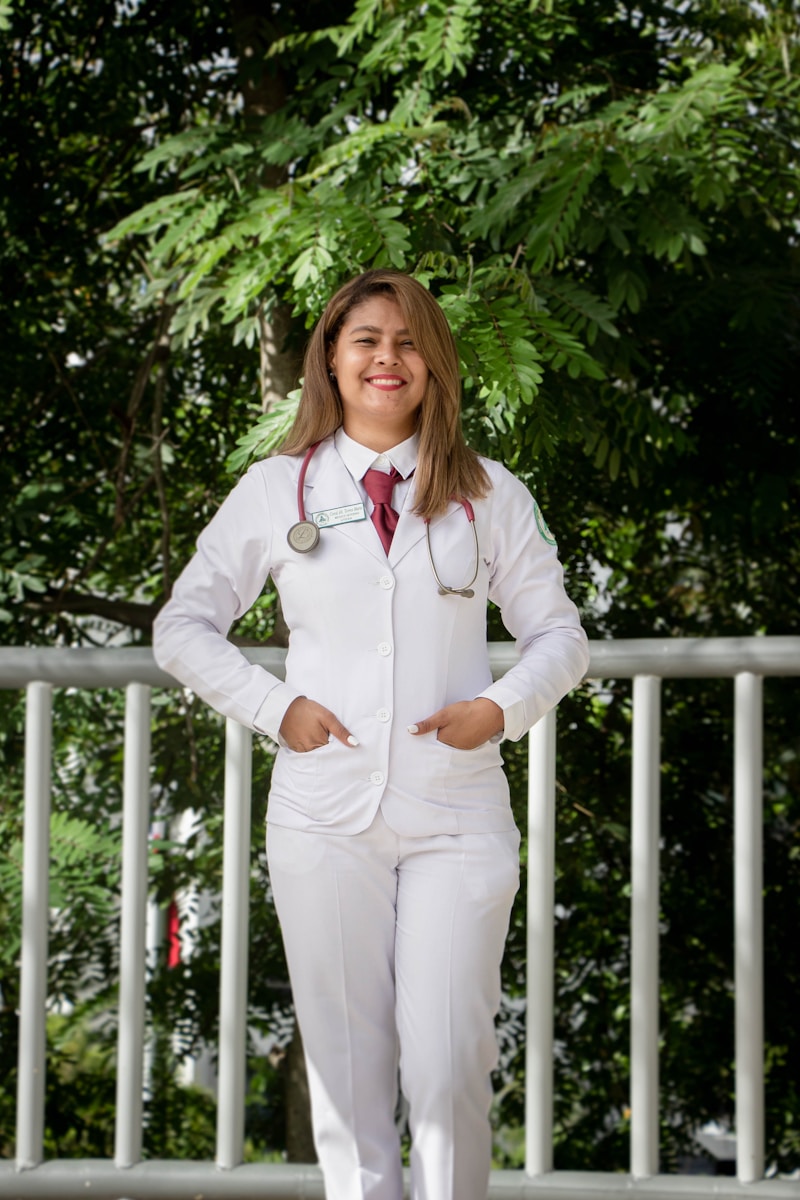 Photo by Siednji Leon woman in white dress shirt and white pants standing near white wooden fence during daytime